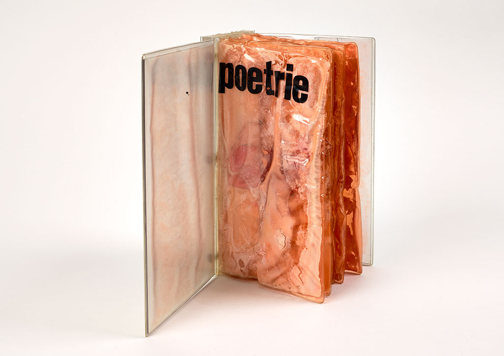A book with a Plexiglas exterior stands upright with the cover open to reveal distressed pages of plastic-sealed cheese. The title poetrie appears in lowercase letters across the top of the first page. 