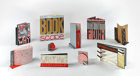 A series of handmade books takes the form of small buildings, together creating a cityscape composed of cardboard, metal, paper, and texts.