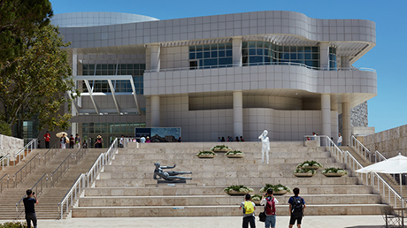 Wide view of a multistoried white building with stone stairs spanning the width of the photo.