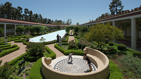 Garden with mostly greenery, a reflecting pool in the background, and circular seating area in the foreground.