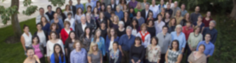 blurred photo of staff members standing together in a group outside of our offices