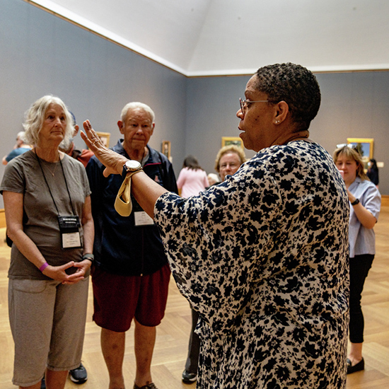 A woman stands before an older man an woman speaking