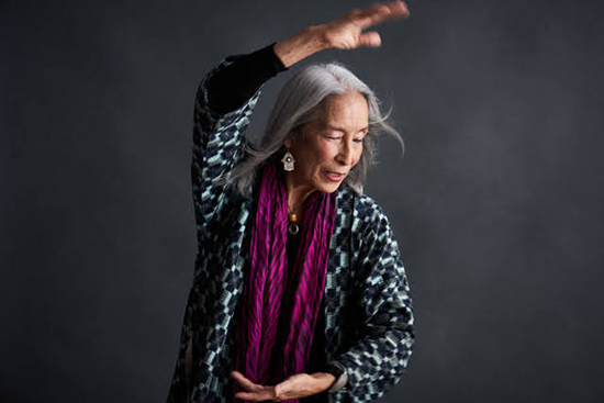 A woman with long gray hair stretching her arm over her head