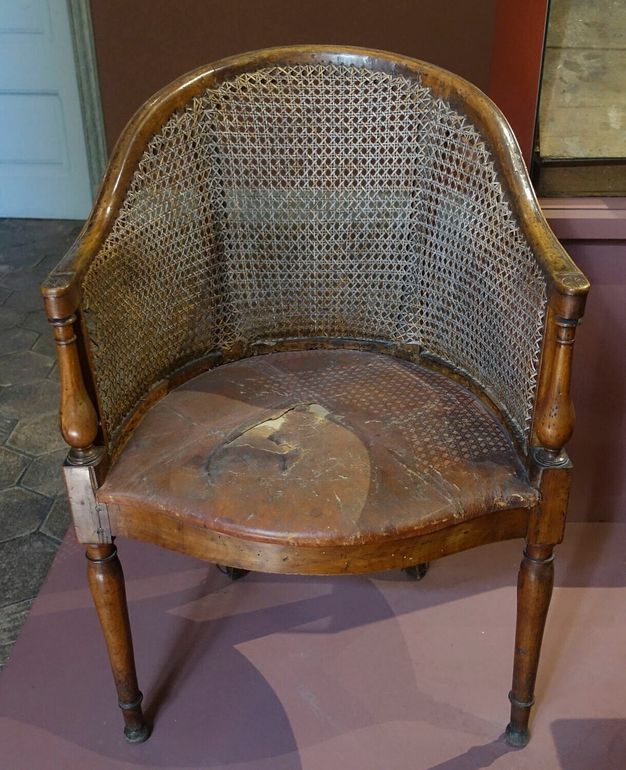 Armchair which structure is made of wood, its back consists of a single cane layer, and its upholstered seat is covered with leather.