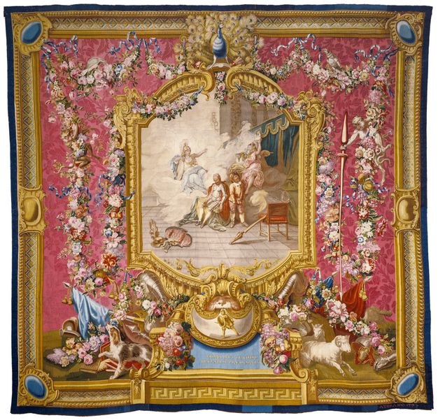 Tapestry featuring in the center two men standing in a palatial room and two women who appear above them in a sea of clouds. The scene is enclosed in a golden frame and surrounded by abundant flower garlands set before a damask-covered pink wall.