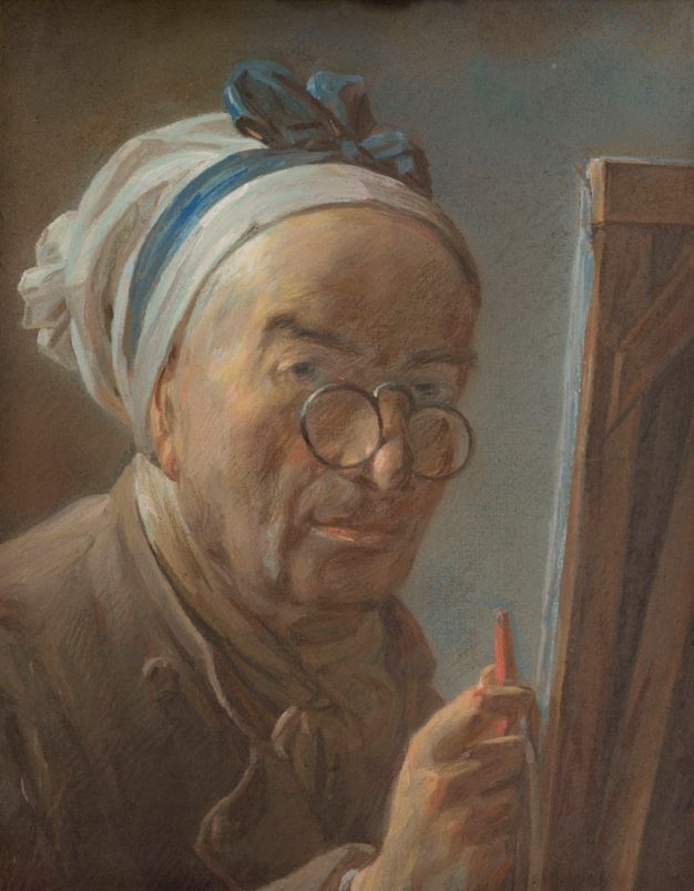 Close up portrait of a man. He is shown looking to the left of the canvas that is placed in front of him and holding a tool on his right hand. His head is covered and he wears round, metal glasses that pinch at the nose.