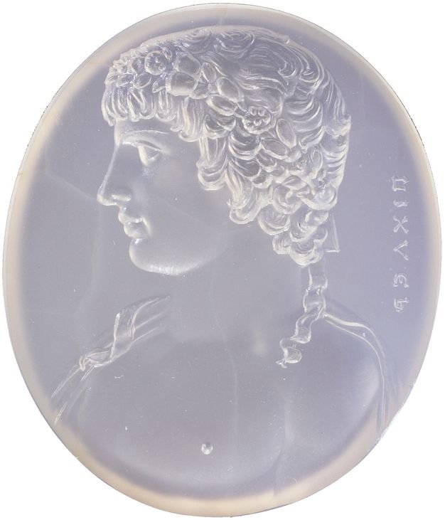 Lilac oval gem engraved with the portrait in profile of a man looking to the left. He has short hair and appears to be topless, but with drapery hanging from his shoulders. A line of text can be seen to the right edge of the gem.