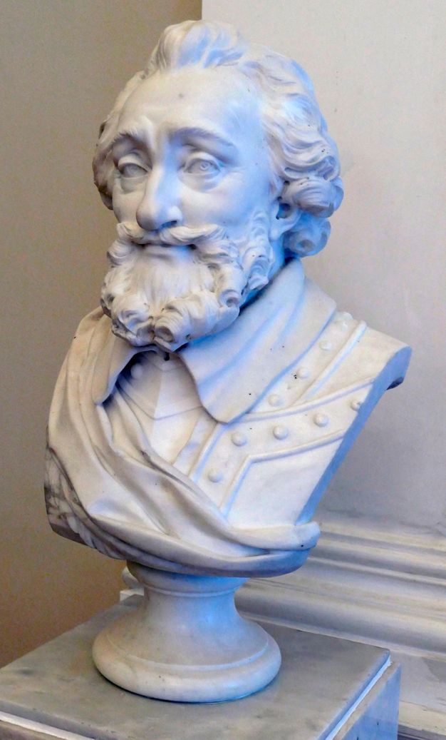 White bust of a bearded man. He wears what appears to be military attire with a sash over it.