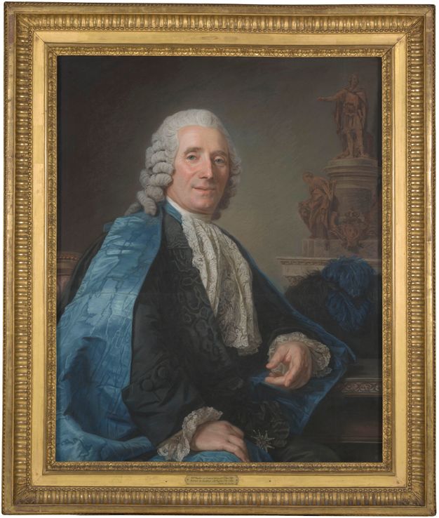 Portrait of a man wearing a powdered wig, lace jabot and cuffs, a black suit with a moire pattern, and a blue silk robe. A decoration of the kind in Figure 37 is attached to his jacket. A blue feather hat is placed behind him. In the background, to the right of the painting, there is a monument in a neoclassic style featuring two statues.