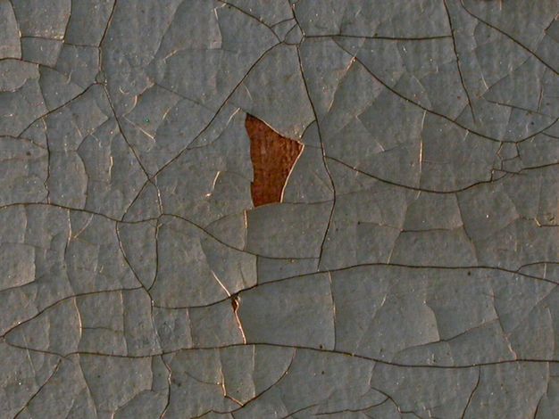 Photograph close-up of a cracking oil painting. Blue paint is chipping off, revealing the browning canvas.