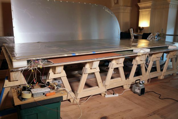 Photo of a long, wodden table. The metal lining for the painting in figure 12.1 is atop the table.