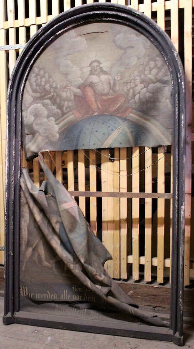 Photo of a torn religious painting. The top, curved half of the painting remainds intact while the bottom half drapes downward, torn.