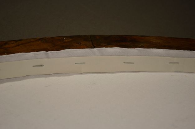 Close up photo depicting the painting (13.1) lining, now secured with staples.