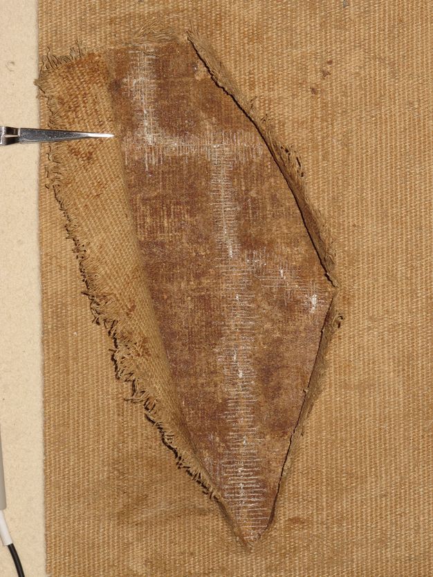 Close up photo of damaged painting lining mended with thread.