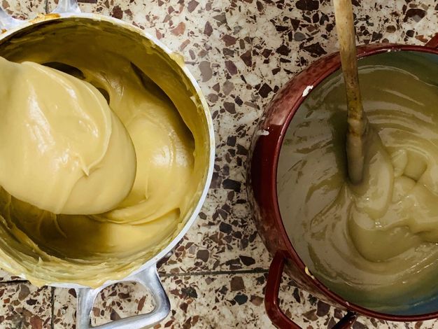 Close up photo of two containers (white and red) with yellowish glue and spoons. 