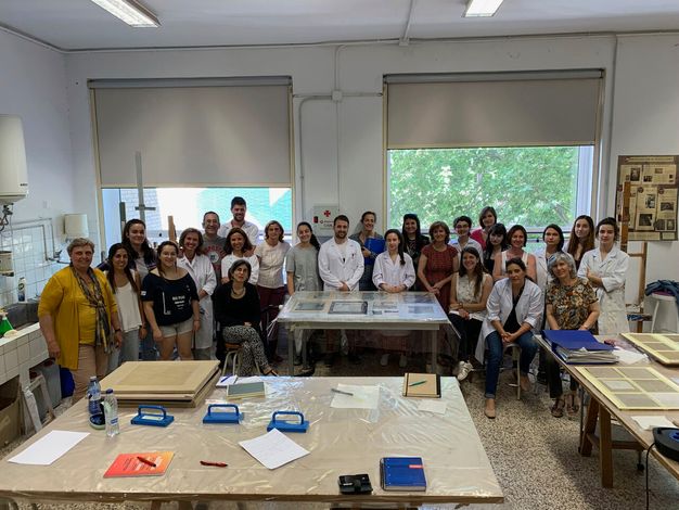 Wide photo of a group of people standing inside a consservation workshop.