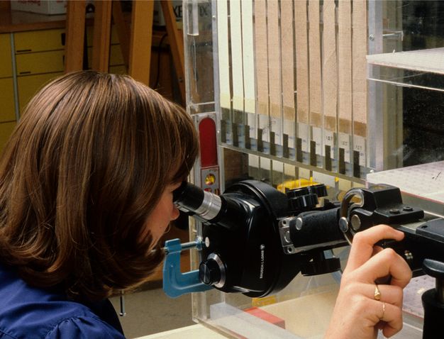 Close up photo of a woman examining film through an inspection microscope.