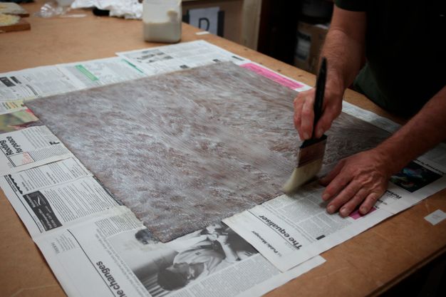 Photo of a conservator's hands as they brush the back of the portrait with adhesive.