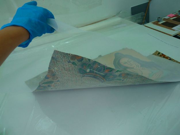 Photo of a conservator holding the clear lining of the painting.