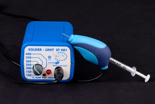 A device for applying adhesive. One portion is an applicator with a syringe-like design, attached by wire to a solder unit that allows a selection of temperatures from 100 to 400 degrees celsius.
