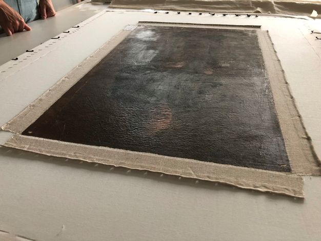 A wider photograph of a painting after lining treatment. The canvas has a smoother surface.