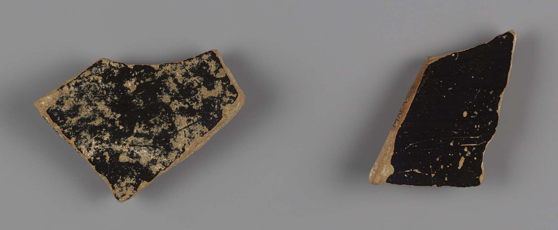 The back side of the two pottery fragments, one mostly black, the other is mottled