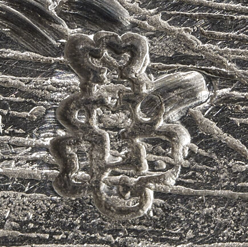 Close-up of the initials JCF entwined in a compact design and stamped on a stand for a sauceboat.