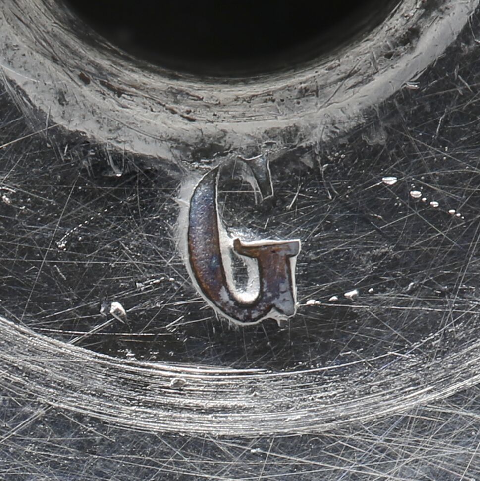 Close-up of the letter G stamped on the girandole.