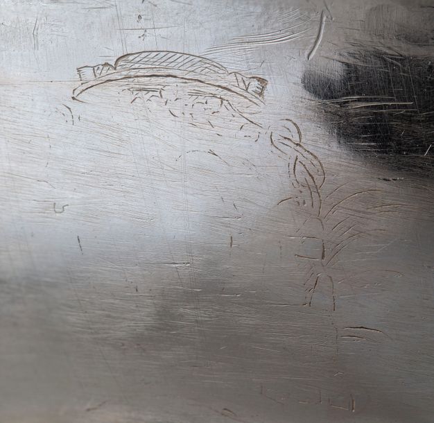 Close-up of a faded engraving of a hat with tassels attached to its right side.