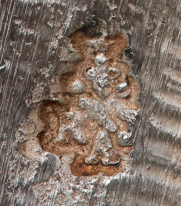 Close-up of the initials RAJ entwined in a compact design and stamped on a giradole.