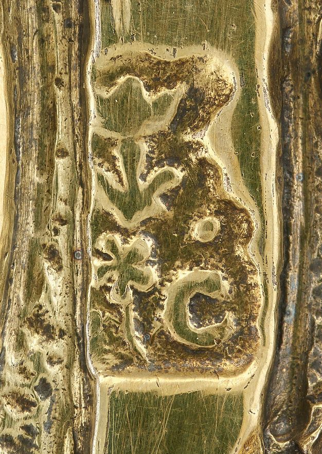 Close-up of the partially obstructed initials LC topped with a flower and stamped on a broth bowl.