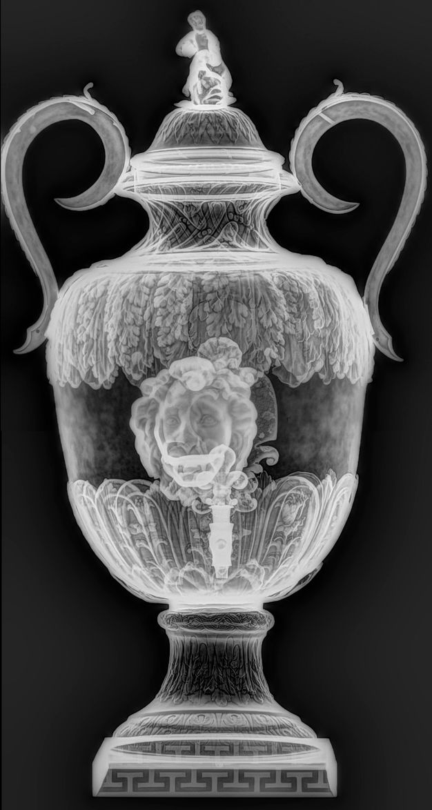 X-radiograph of a silver fountain with two handles, an adolescent on the lid, a lion in the center, and a tap below the lion.