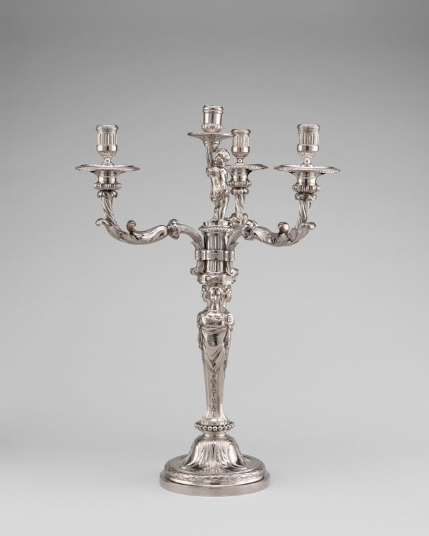 Four candelabra, one of which is held by a putto, branch off from a base held up by three women standing back to back.
