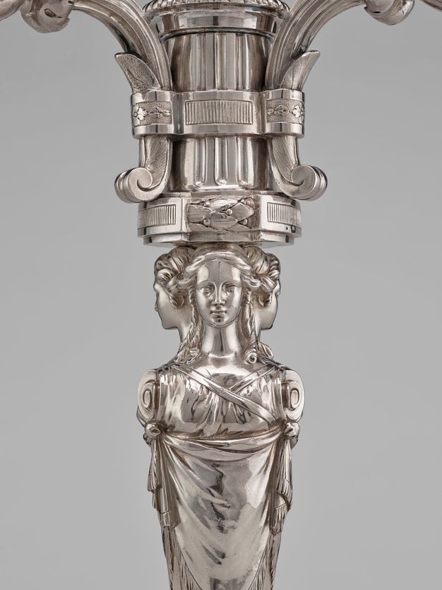 Close-up of the three women standing back to back wearing braided hair crowning their head, curly hair down their neck, and a crossover v-neck dress.