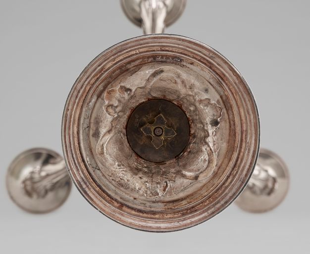 Bottom view of the girandole, revealing a screw shaped like a cross.