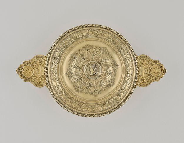 Lidded bowl with two handles ornamented with male and female profiles respectively, a female profile on the knob, two rings of decorative engravings, and a band of vines and spheres around the edge.