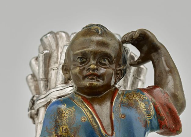 Young man with blue eyes and red lips wearing a blue tunic with red and gold accents.