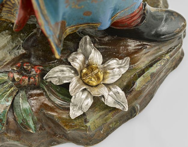 Red flower with green leaves and white flower with yellow center on the base of the sugar caster.
