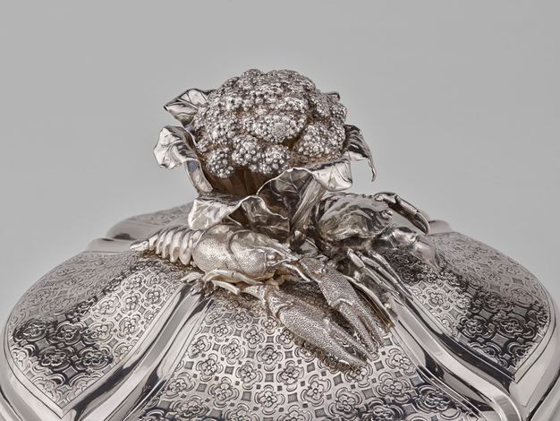 Lid of the tureen topped by a cauliflower, lobster, and a crab on a floral pattern.