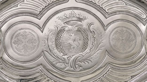 Close-up of the tray's center design with two circles with waving flutes surrounding a circle with a coat of arms.