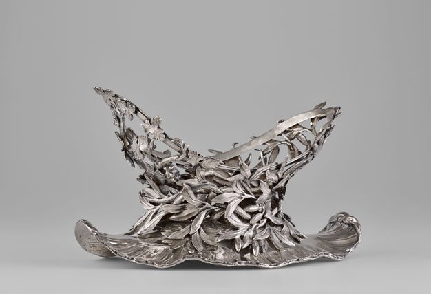 Stand with a v-shaped mouth covered in leafy olive branches with fruit on top of a shell-edged base.