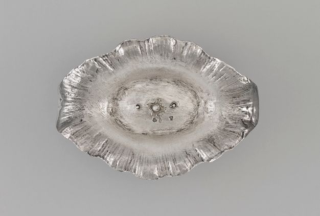 Top view of the oval-shaped base of the stand with three screws at the center.