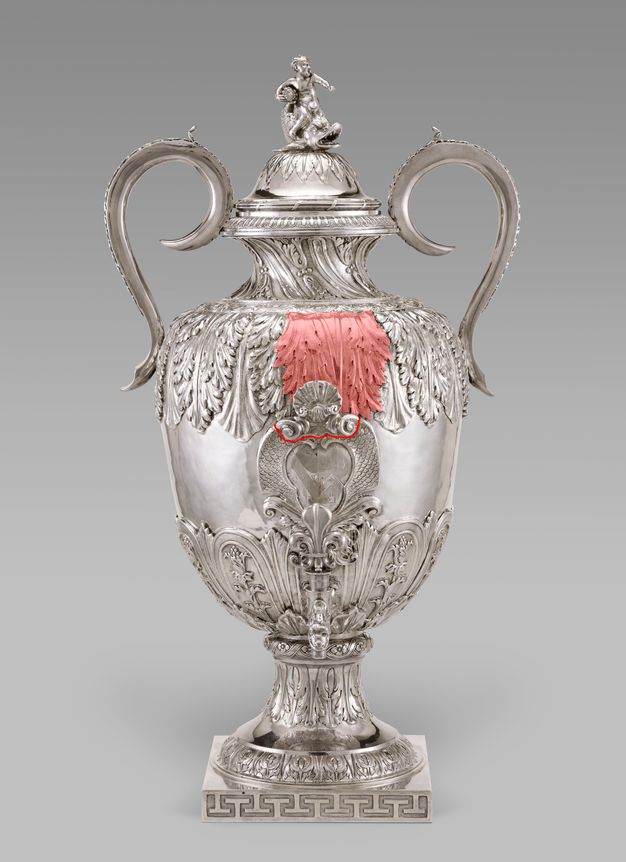 Silver fountain with two leaves on the main body of the vessel highlighted red and a red bracket marking the meeting point of a shell and the central design of the vessel.