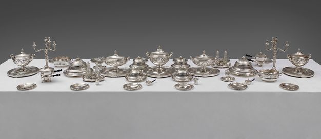 Place setting for twelve with girandoles at each end, five lidded tureens, and and several smaller vessels.