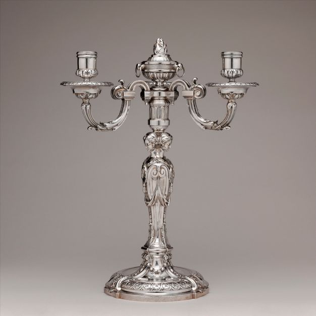 Silver girandole with three candle cups branching from a base of three women standing back to back and topped with an artichoke.