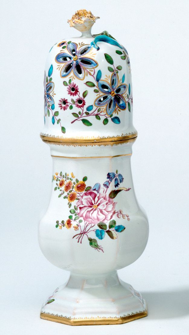 White sugar caster with gold decoration along its edges and vibrant blue, pink, and orange flowers on its body.