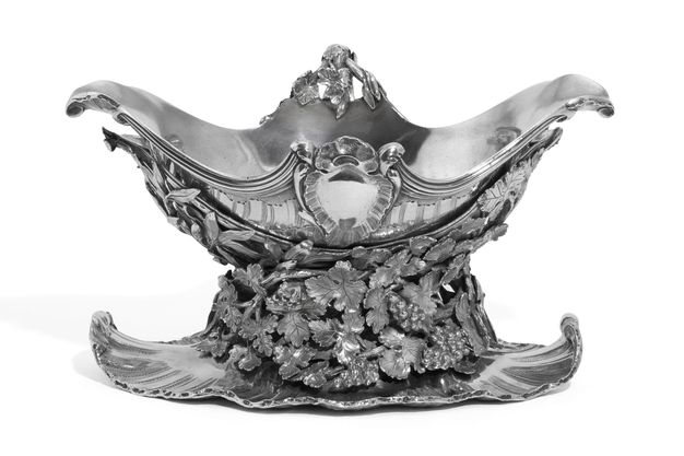 Silver sauceboat on a stand with an armorial cartouche decorating its midpoint, a cradle covered in grape leaves and grapes, and a shell-edged base.