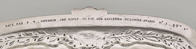 Letters and numbers inscribed under the stand's rim above a ring of laurel branches.