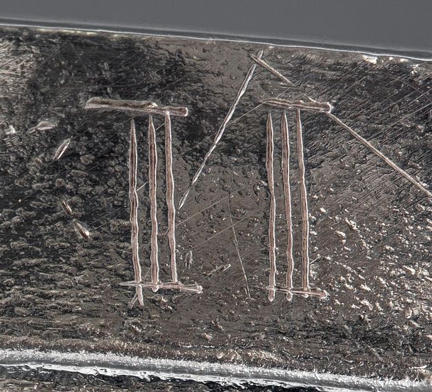 Close-up of two Roman numeral III's scratched on the lid.