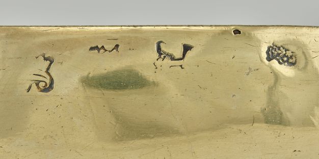 Close-up of the bowl's exterior edge, detailing four stamped symbols.